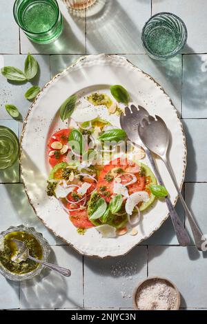 Vue de dessus de la salade espagnole appétissante avec des ingrédients variés et des tomates servies sur une assiette en céramique avec une cuillère Banque D'Images