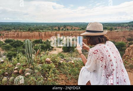 Vue arrière d'une touriste féminine méconnue prenant des photos de cactus poussant dans le désert de Tatacoa en Colombie Banque D'Images