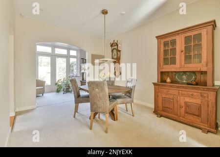 Intérieur de salle à manger avec table ronde et chaises sous lustre près du placard dans l'appartement lumineux Banque D'Images