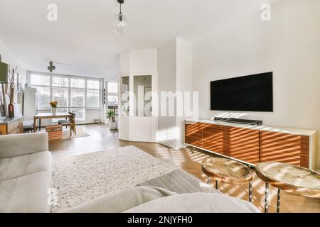 Intérieur d'un salon moderne avec canapé confortable et TV près d'une table à manger avec chaises dans un appartement moderne Banque D'Images