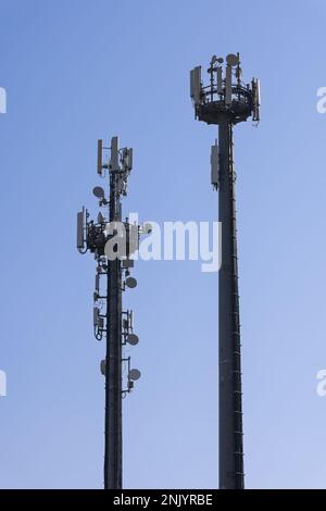 Tour de télécommunications avec antennes cellulaires et répéteurs contre un ciel bleu clair (photos verticales) Banque D'Images