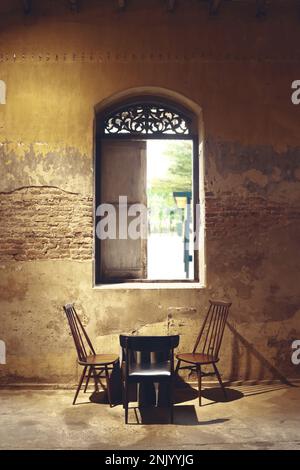 une table et trois chaises sont mis sous la fenêtre antique dans le café pop up Banque D'Images