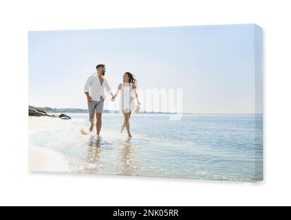 Photo imprimée sur toile, fond blanc. Un jeune couple heureux qui court sur la plage près de la mer Banque D'Images