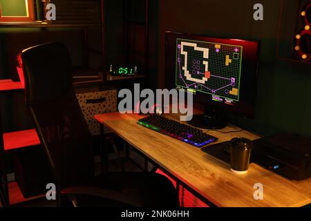 Ordinateur moderne et clavier RVB sur une table en bois dans une pièce sombre Banque D'Images