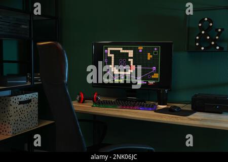 Ordinateur moderne et clavier RVB sur une table en bois dans une pièce sombre Banque D'Images