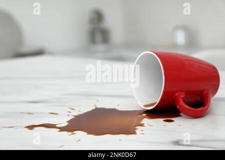 Tasse renversée et café renversé sur table en marbre blanc dans la cuisine, espace pour le texte Banque D'Images