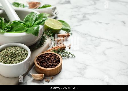 Différentes épices et herbes naturelles sur une table en marbre blanc. Espace pour le texte Banque D'Images