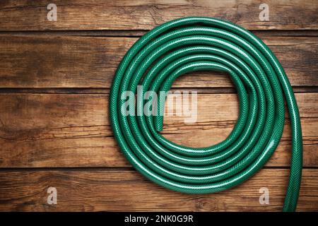 Tuyau de jardin vert sur table en bois, vue de dessus Banque D'Images