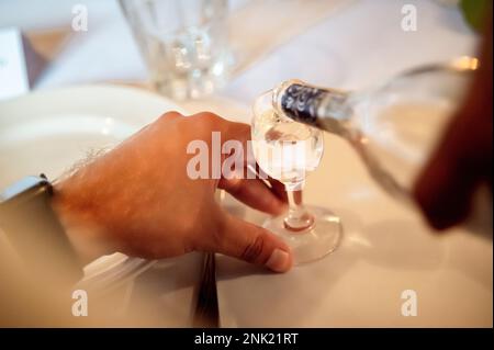 mains d'un homme qui verse de l'alcool dans un verre Banque D'Images