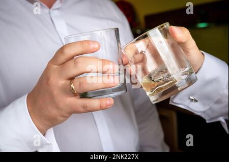 mains de deux hommes qui toastent à partir de lunettes à whisky Banque D'Images