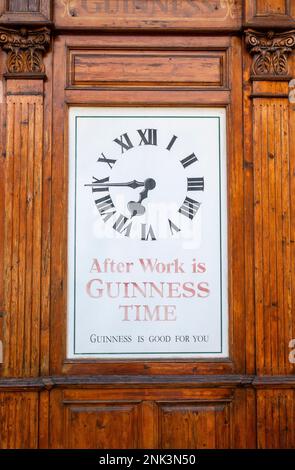 Horloge Guinness vintage construite dans des panneaux en bois proclame après le travail est GUINNESS TIME Banque D'Images