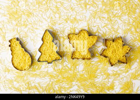 Les formes créatives de noël se façonnent avec des pâtes à l'intérieur, sur fond blanc. Concept créatif de la cuisine de noël. Copier l'espace Banque D'Images