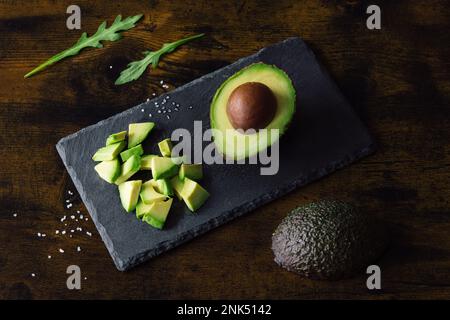 Des moitiés d'avocat sur une planche à découper en bois. Arrière-plan marron. Vue de dessus. Espace pour le texte. Photo de haute qualité Banque D'Images