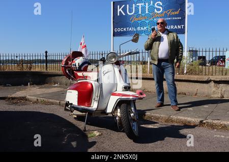 Un scouteur sur son téléphone mobile après être arrivé tôt au terminal de ferry de l'île de Wight à Southampton sur son 1965 Lambretta SX125. Banque D'Images