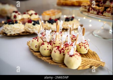 sucreries, gâteaux et biscuits boules sucrées sur un bâton dans le chocolat blanc avec des saupoudrés Banque D'Images