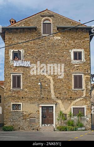 Femme dans la vieille maison pendante vêtements sur la ligne de lavage dans la ville Koper / Capodistria, péninsule d'Istrie, Obalnokraška, littoral / Primorska, Slovénie Banque D'Images