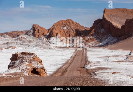 Route traversant la Valle de la Luna (Vallée de la Lune) et dépôt de sel sur le sol, désert d'Atacama. Région d'Antofagasta. Chili Banque D'Images