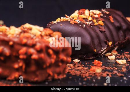 Le gâteau au chocolat apparaît avec des noix sous forme de popsicle sur le bâton sur fond de tableau noir d'ardoise, gros plan. Сan Voir la texture interne. Banque D'Images