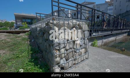 De nombreuses pierres empilées derrière la cage de fils à l'extérieur près du pont. Pierre de granit gris derrière les barres. Maillage métallique avec pierres Banque D'Images