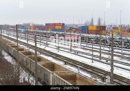 Gare de déchargement et de chargement de fret. Sur la plate-forme il y a des wagons avec des voitures, des wagons vides, des conteneurs déchargés à proximité sur la plate-forme. Banque D'Images
