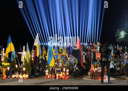 Lviv, Ukraine 23 février 2023. Des membres de la famille visitent les tombes de soldats tombés dans le cimetière du champ de Lychakiv où des centaines de soldats ukrainiens morts au cours de la dernière année sont enterrés lors d'un événement de commémoration, alors que des « rayons de mémoire » symboliques ont été illuminés au cimetière militaire de Lychakiv pour marquer le premier anniversaire de La guerre de la Russie contre l'Ukraine. La Russie a envahi l'Ukraine le 24 février 2022, déclenchant la plus grande attaque militaire en Europe depuis la Seconde Guerre mondiale Banque D'Images