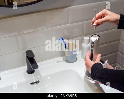 Une jeune femme change les mains de sa pointe d'eau dentaire domestique plus fine Banque D'Images