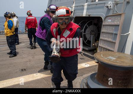 220813-N-EH998-1014 GOLFE D'ADEN (13 août 2022) des marins transportent un tuyau de ravitaillement sur le pont de vol à bord du destroyer à missile guidé USS Nitze (DDG 94) dans le golfe d'Aden, août 13. Nitze est déployé dans la zone d'opérations de la flotte américaine 5th afin d'assurer la sécurité et la stabilité maritimes dans la région du Moyen-Orient. Banque D'Images