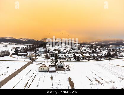 Quartier résidentiel couvert de neige, avec vue aérienne sur le ciel jaune Banque D'Images