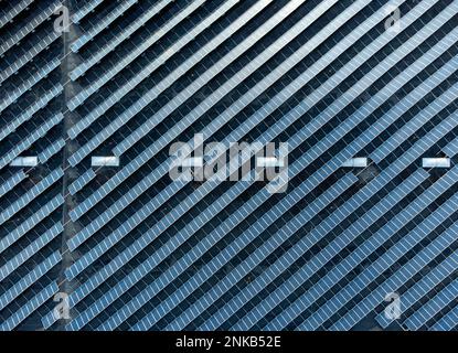 Grande ferme empilée de panneaux solaires sur un bâtiment d'entrepôt de distribution, vue aérienne en haut vers le bas Banque D'Images