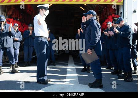 ÉTATS-UNIS Maître de classe 3rd de la Garde côtière Nicholas Hillman, un compagnon d’électricien à bord de l’ours USCGC (WMEC 901), rend hommage à son commandant Cmdr. Brooke Millard alors que ses compagnons de navire claque en arrière-plan, Nuuk (Groenland), le 12 août 2022. Hillman venait d'être avancé du rang de pompier à la classe de petit officier 3rd. Banque D'Images