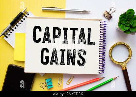 Gains en capital - augmentation de la valeur d'un actif en capital et réalisée lors de la vente de l'actif, concept textuel sur le bloc-notes Banque D'Images