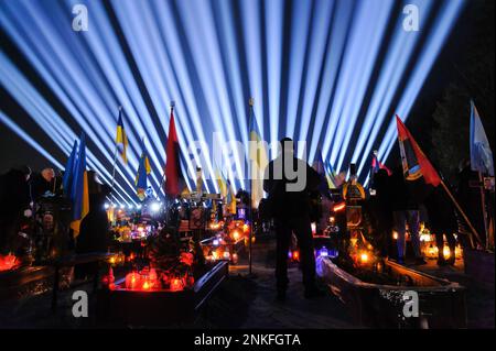 Lviv, Ukraine. 23rd févr. 2023. L'homme visite les tombes des soldats tombés au cimetière du champ de Lychakiv où des centaines de soldats ukrainiens morts au cours de la dernière année sont enterrés lors d'un événement de commémoration alors que des « rayons de mémoire » symboliques ont été illuminés au cimetière militaire de Lychakiv pour marquer le premier anniversaire de La guerre de la Russie contre l'Ukraine. La Russie a envahi l'Ukraine le 24 février 2022, déclenchant la plus grande attaque militaire en Europe depuis la Seconde Guerre mondiale Crédit : SOPA Images Limited/Alamy Live News Banque D'Images