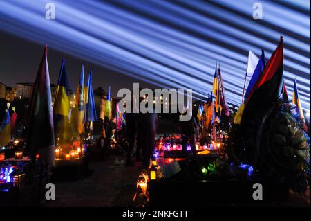 Lviv, Ukraine. 23rd févr. 2023. Les gens visitent les tombes des soldats tombés au cimetière du champ de Lychakiv où des centaines de soldats ukrainiens morts au cours de la dernière année sont enterrés lors d'un événement de commémoration alors que des « rayons de mémoire » symboliques ont été illuminés au cimetière militaire de Lychakiv pour marquer le premier anniversaire de La guerre de la Russie contre l'Ukraine. La Russie a envahi l'Ukraine le 24 février 2022, déclenchant la plus grande attaque militaire en Europe depuis la Seconde Guerre mondiale Crédit : SOPA Images Limited/Alamy Live News Banque D'Images