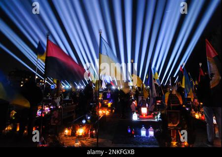 Lviv, Ukraine. 23rd févr. 2023. Les gens visitent les tombes des soldats tombés au cimetière du champ de Lychakiv où des centaines de soldats ukrainiens morts au cours de la dernière année sont enterrés lors d'un événement de commémoration alors que des « rayons de mémoire » symboliques ont été illuminés au cimetière militaire de Lychakiv pour marquer le premier anniversaire de La guerre de la Russie contre l'Ukraine. La Russie a envahi l'Ukraine le 24 février 2022, déclenchant la plus grande attaque militaire en Europe depuis la Seconde Guerre mondiale Crédit : SOPA Images Limited/Alamy Live News Banque D'Images