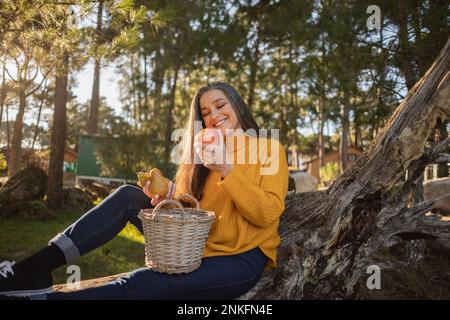 Femme mûre souriante tenant une pomme dans la nature Banque D'Images