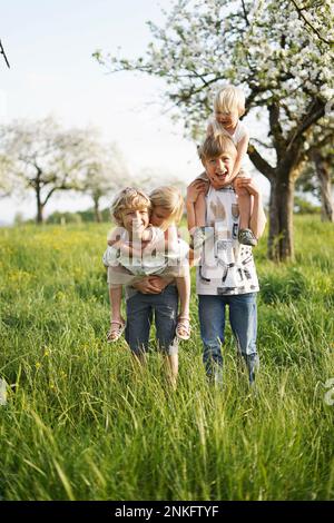 Bonne fille et garçons appréciant ensemble devant un pommier Banque D'Images