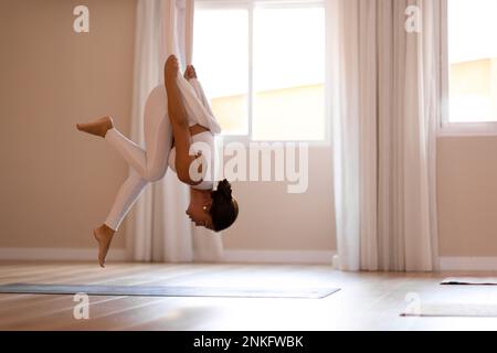 Femme accrochée à l'antenne faisant du yoga en studio Banque D'Images