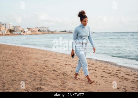Jeune femme marchant sur le sable à la plage Banque D'Images