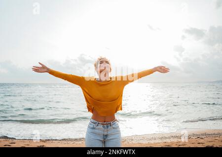 Femme insouciante avec les bras étendus sur la plage Banque D'Images