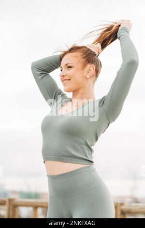 Bonne femme nouant les cheveux debout devant le ciel Banque D'Images