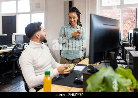 Un jeune homme d'affaires mange de la salade avec un collègue pendant la pause déjeuner Banque D'Images