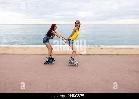 Amis patinage à roulettes et s'amuser sur la promenade en bord de mer Banque D'Images
