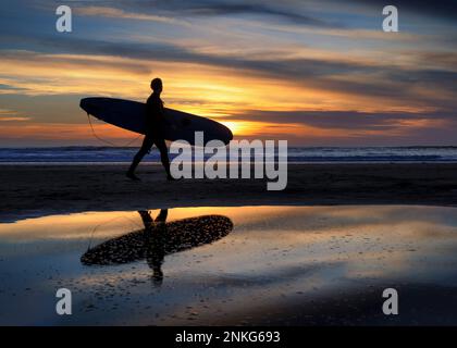 Silhouette de surfeur marchant sur le rivage à la plage Banque D'Images