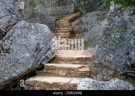 Un sentier en escalier de pierre mène vers le haut de la colline entre les rochers de calcaire géologique dans le parc national de Pedernales Falls dans le Texas Hill Country. Banque D'Images