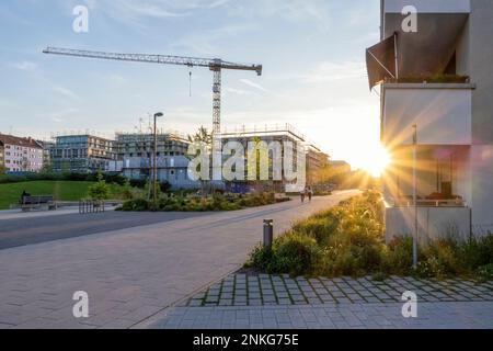 Allemagne, Bavière, Munich, pavé dans la zone résidentielle au coucher du soleil avec grue industrielle debout en arrière-plan Banque D'Images