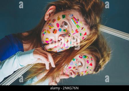 Femme avec des autocollants sur le visage et le doigt sur les lèvres sur fond bleu Banque D'Images