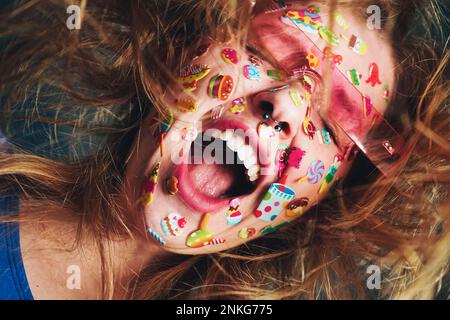 Femme gaie avec des autocollants sur le visage portant des lunettes de soleil Banque D'Images