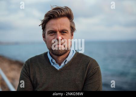 Homme mûr souriant en face de la mer Banque D'Images