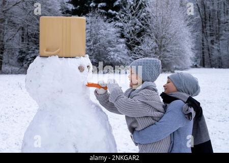 Frère et sœur faisant bonhomme de neige Banque D'Images