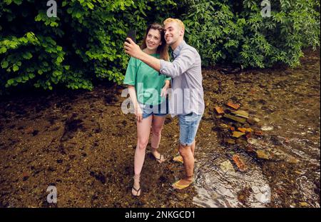 Un jeune couple prend le selfie à travers un téléphone intelligent en train de couler Banque D'Images